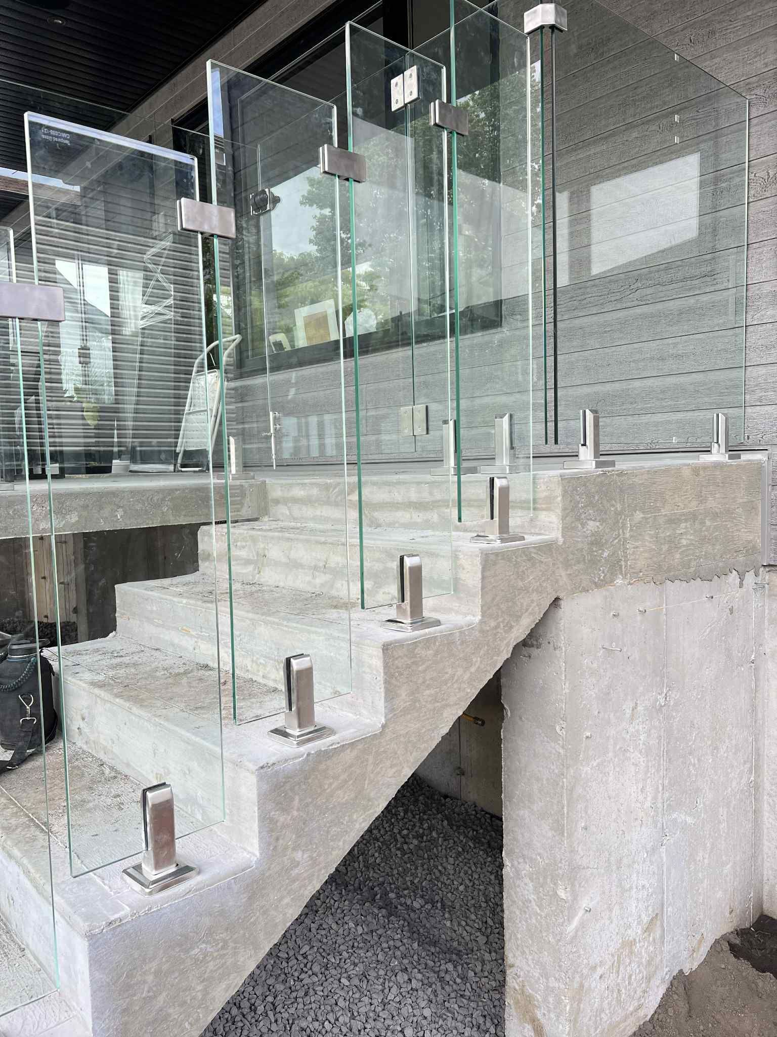Escalier en verre avec poteaux métalliques et murs en béton dans l'intérieur d'un bâtiment moderne