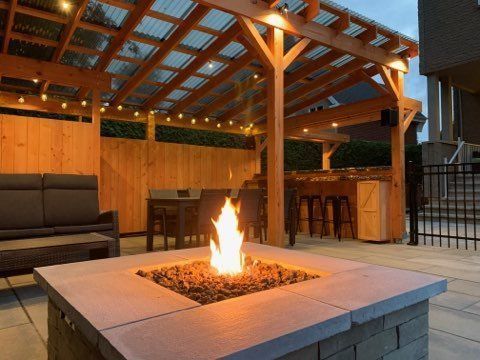 Terrasse extérieure avec un foyer allumé sous une pergola en bois au crépuscule