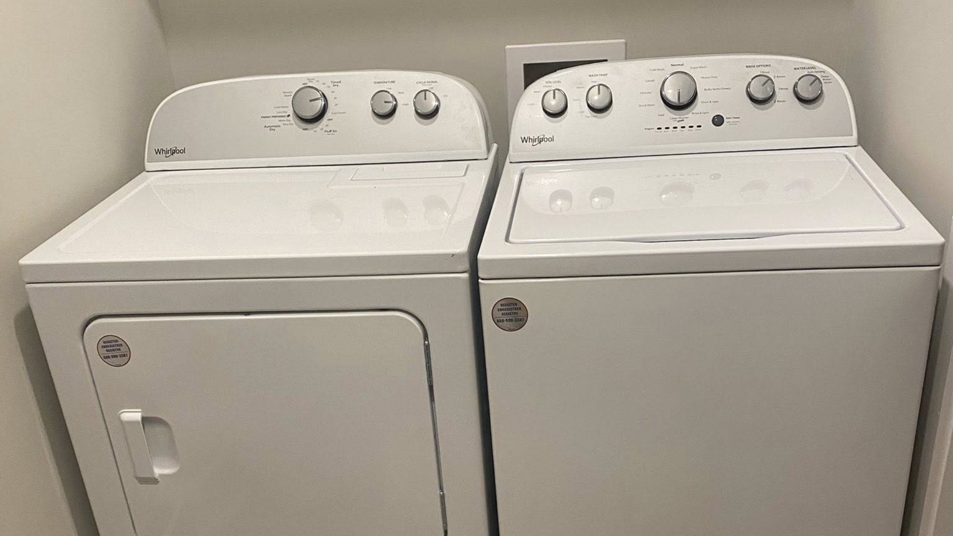 A white clothes dryer and washing machine set placed side-by-side in a laundry room.