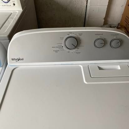 Top-loading Whirlpool dryer control panel with a main cycle dial and two smaller temperature and dryness knobs.