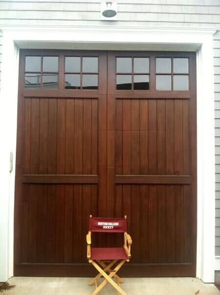 A tall, wooden garage door with glass panes at the top, featuring a red director’s chair centered in front.