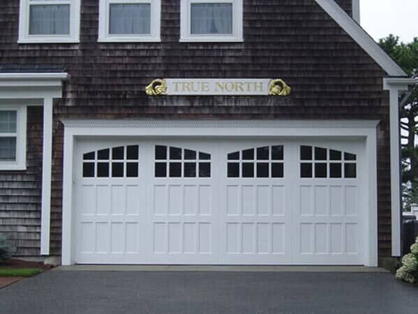 A white carriage-style garage door under a sign that reads 