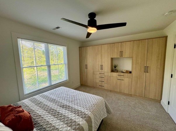A bedroom with a large bed and a ceiling fan.