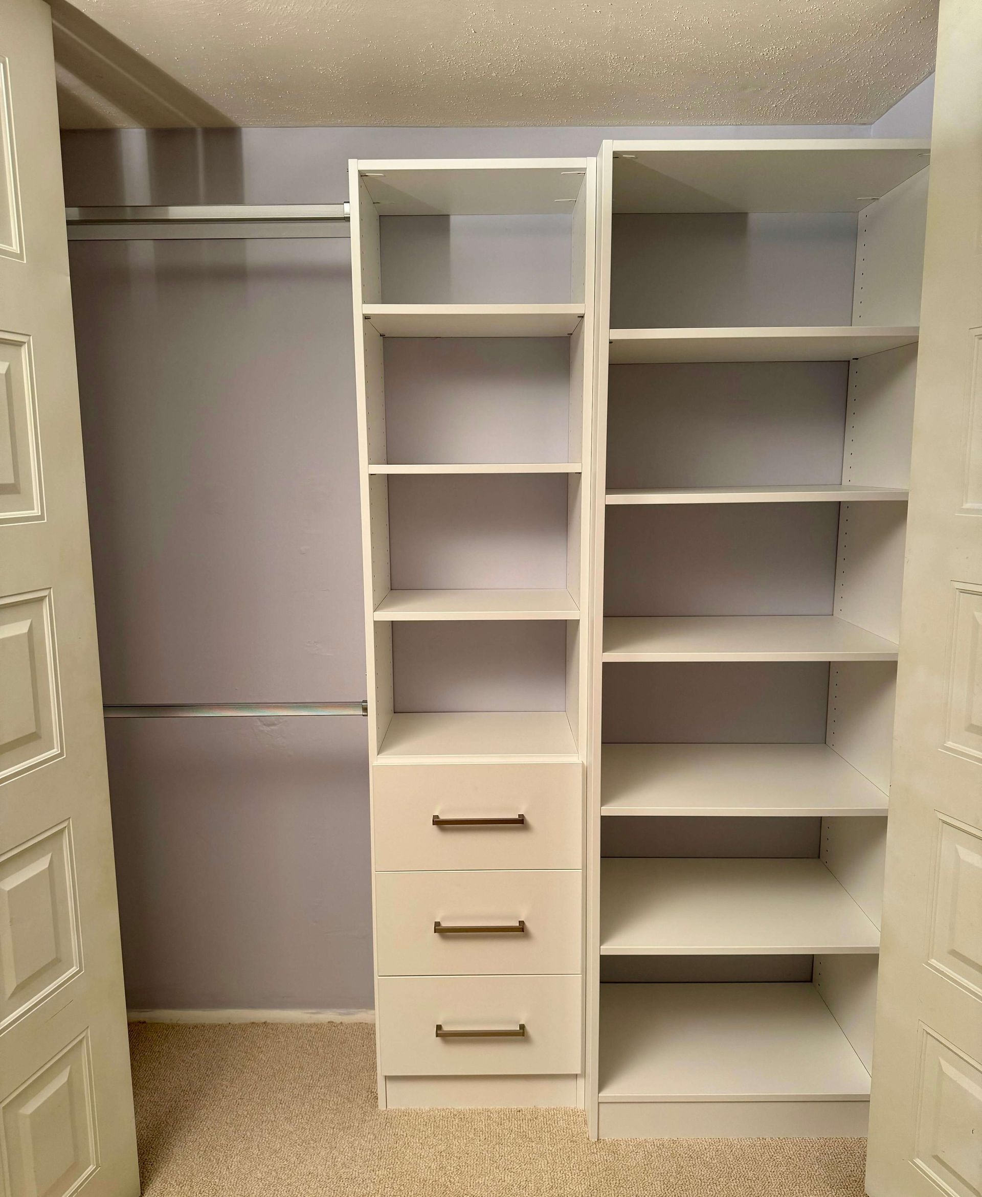 A walk in closet with white shelves and drawers