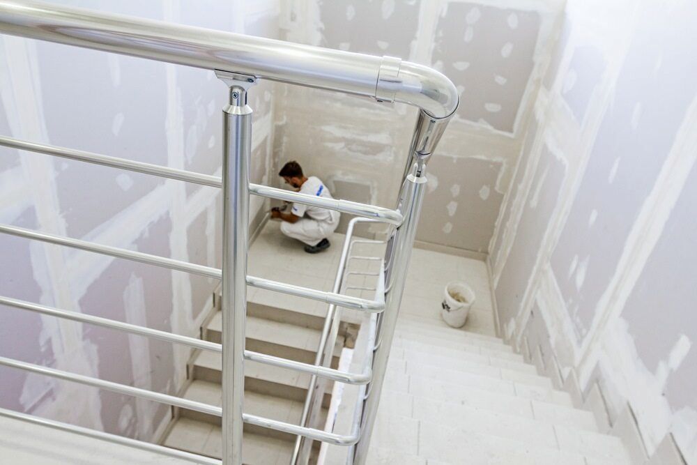 A Man Is Sitting On The Floor Next To A Staircase — L & S Wirth Painting in Cobar, NSW