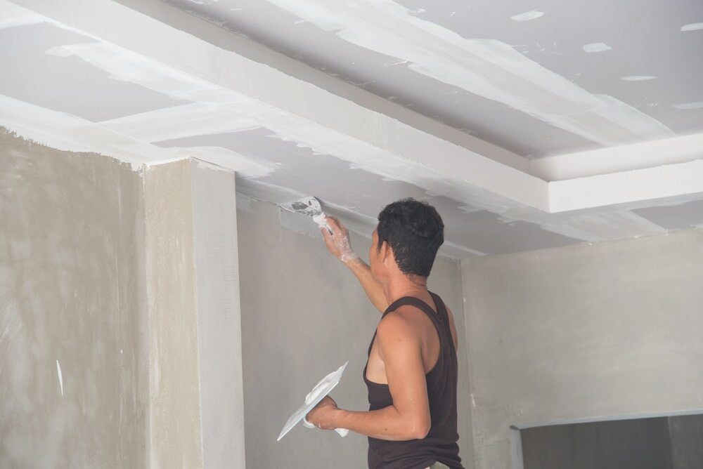 A Man Is Plastering The Ceiling Of A Room With A Trowel — L & S Wirth Painting in Forbes, NSW