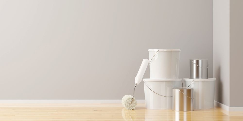 A Bucket Of Paint And A Paint Roller Are Sitting On A Wooden Floor — L & S Wirth Painting in Dubbo, NSW