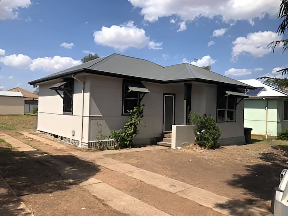 A Small White House With A Gray Roof And A Car Parked In Front Of It — L & S Wirth Painting in Dubbo, NSW