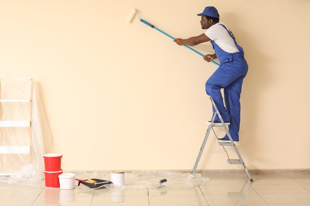 A Man Is Standing On A Ladder Painting A Wall — L & S Wirth Painting in Forbes, NSW