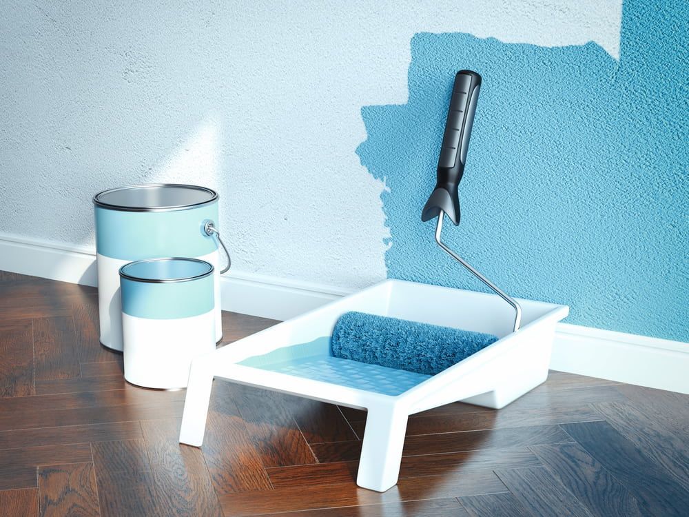 A Paint Roller Is Sitting In A Tray Next To Two Cans Of Paint — L & S Wirth Painting in Bourke, NSW