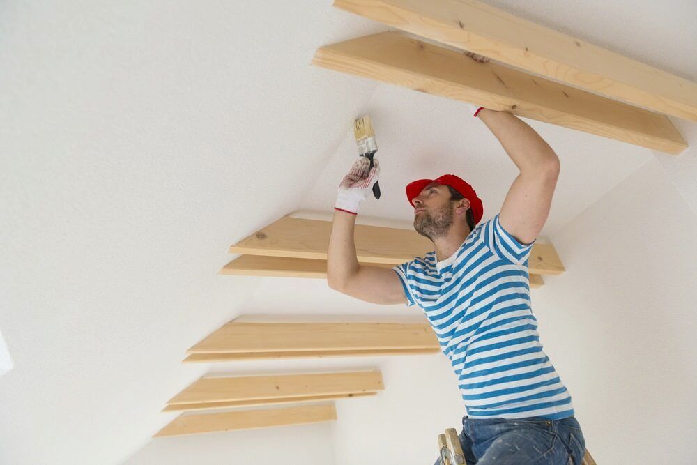 A Man Is Painting The Ceiling Of A Room With A Brush — L & S Wirth Painting in Coonamble, NSW