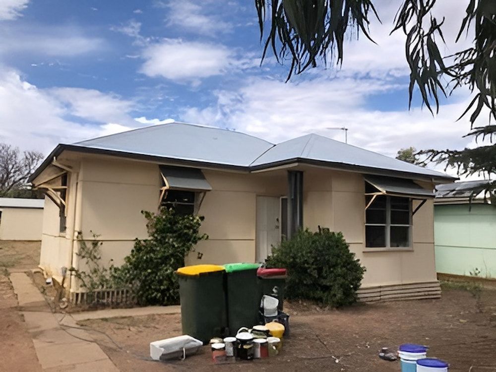 A House With Trash Cans In Front Of It Is Being Painted — L & S Wirth Painting in Dubbo, NSW