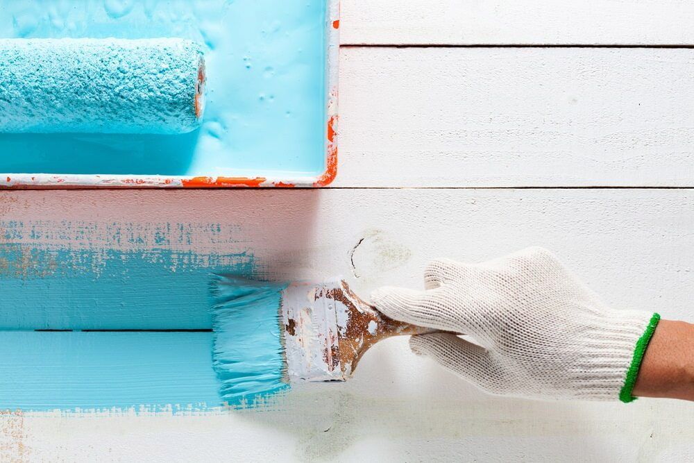 A Person Is Painting A White Wall With A Blue Paint Roller — L & S Wirth Painting in Gilgandra, NSW