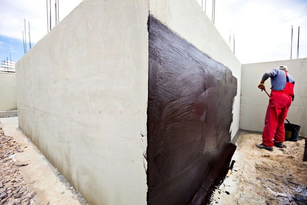 A Man Is Painting A Wall With Black Paint — L & S Wirth Painting in Narromine, NSW