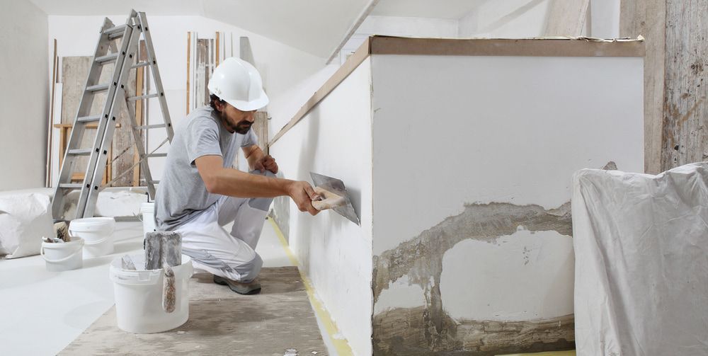 A Man Is Plastering A Wall In A Room — L & S Wirth Painting in Forbes, NSW