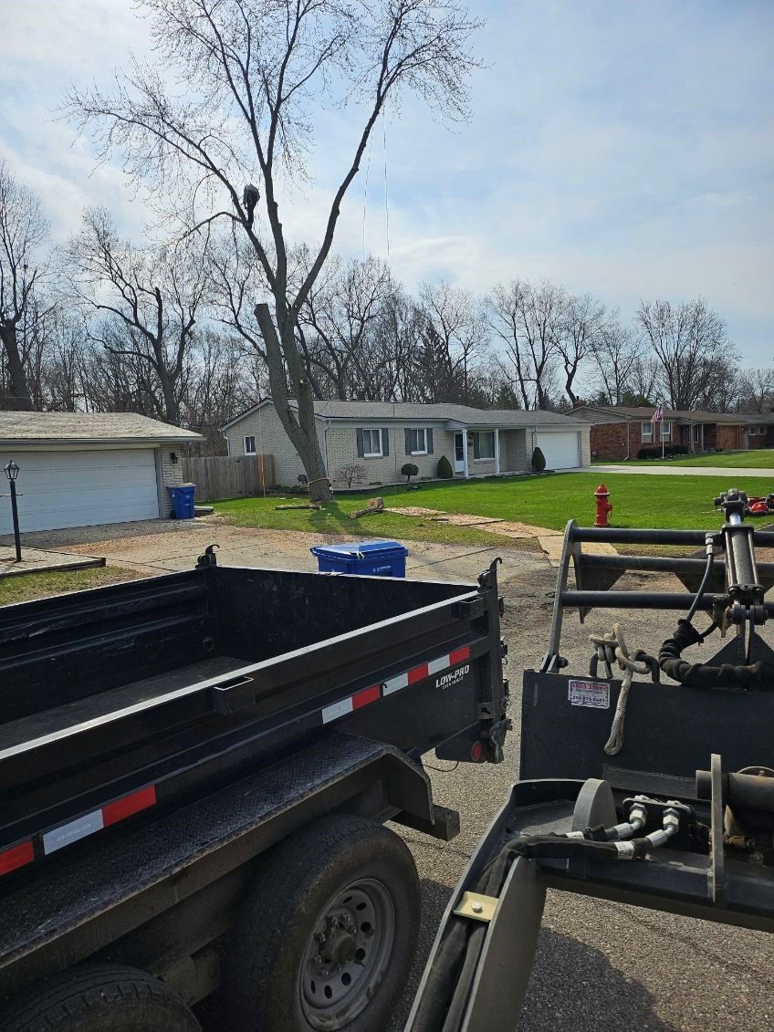 A dump trailer is parked in front of a house.