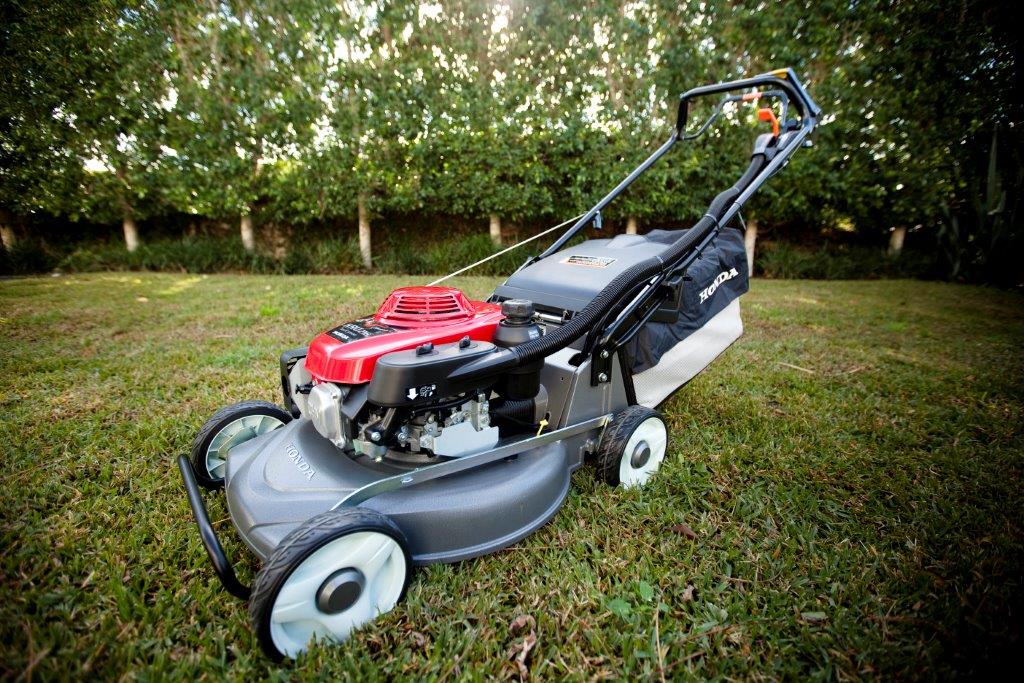 A modern electric lawn mower standing on a backyard lawn