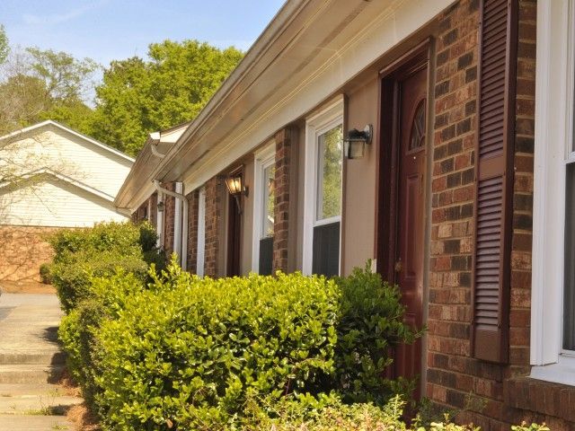 Exterior view of apartment buildings with brick facades and lush landscaping.