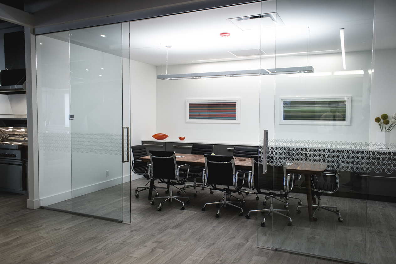 A conference room with a glass wall and tables and chairs.