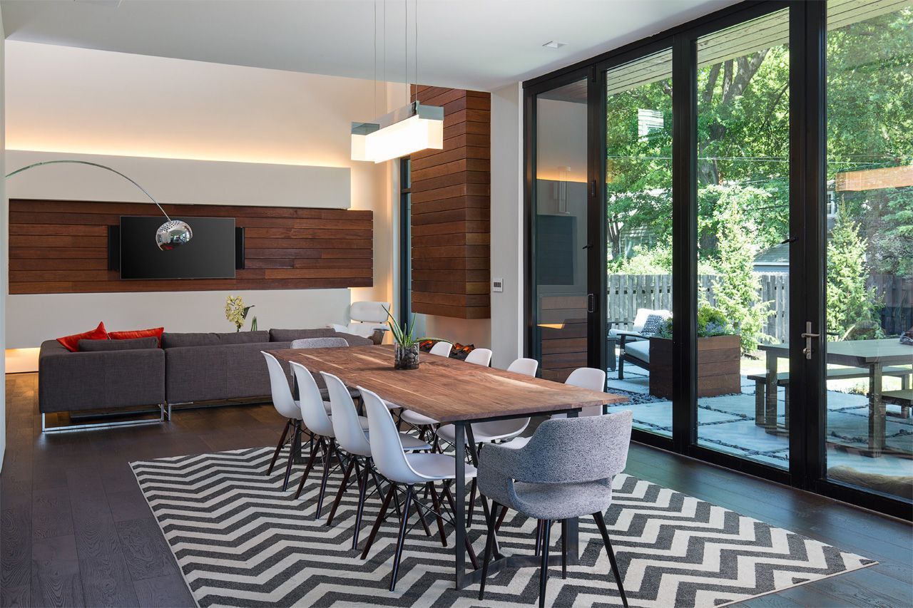 A dining room with a long table and chairs and a rug.