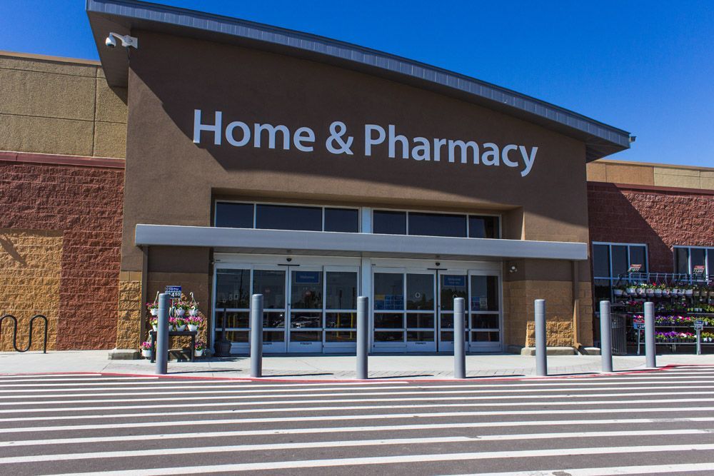 The front of a home and pharmacy store with a parking lot in front of it.