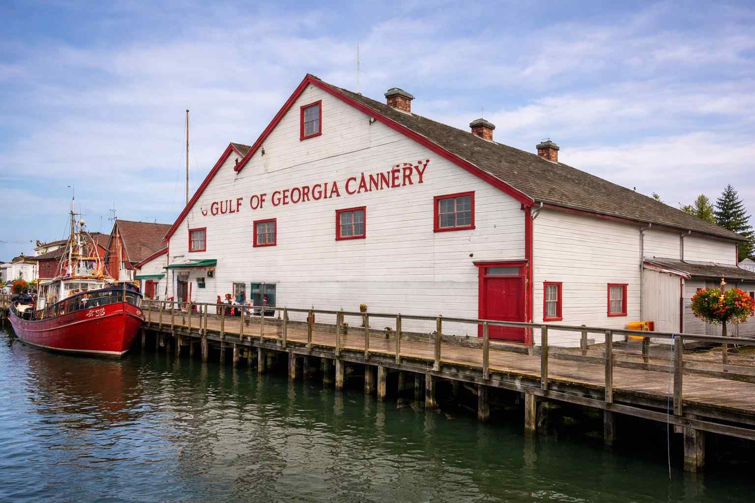Gulf of Georgia Cannery on a waterfront dock with a red boat beside it