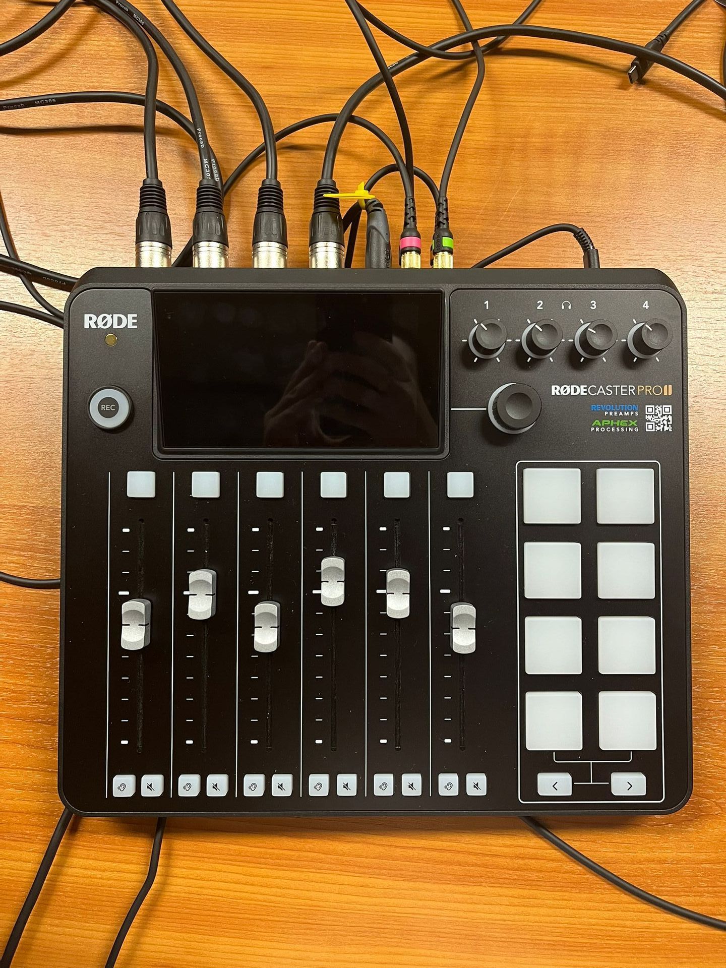 Een rode mixer staat op een houten tafel omgeven door draden.