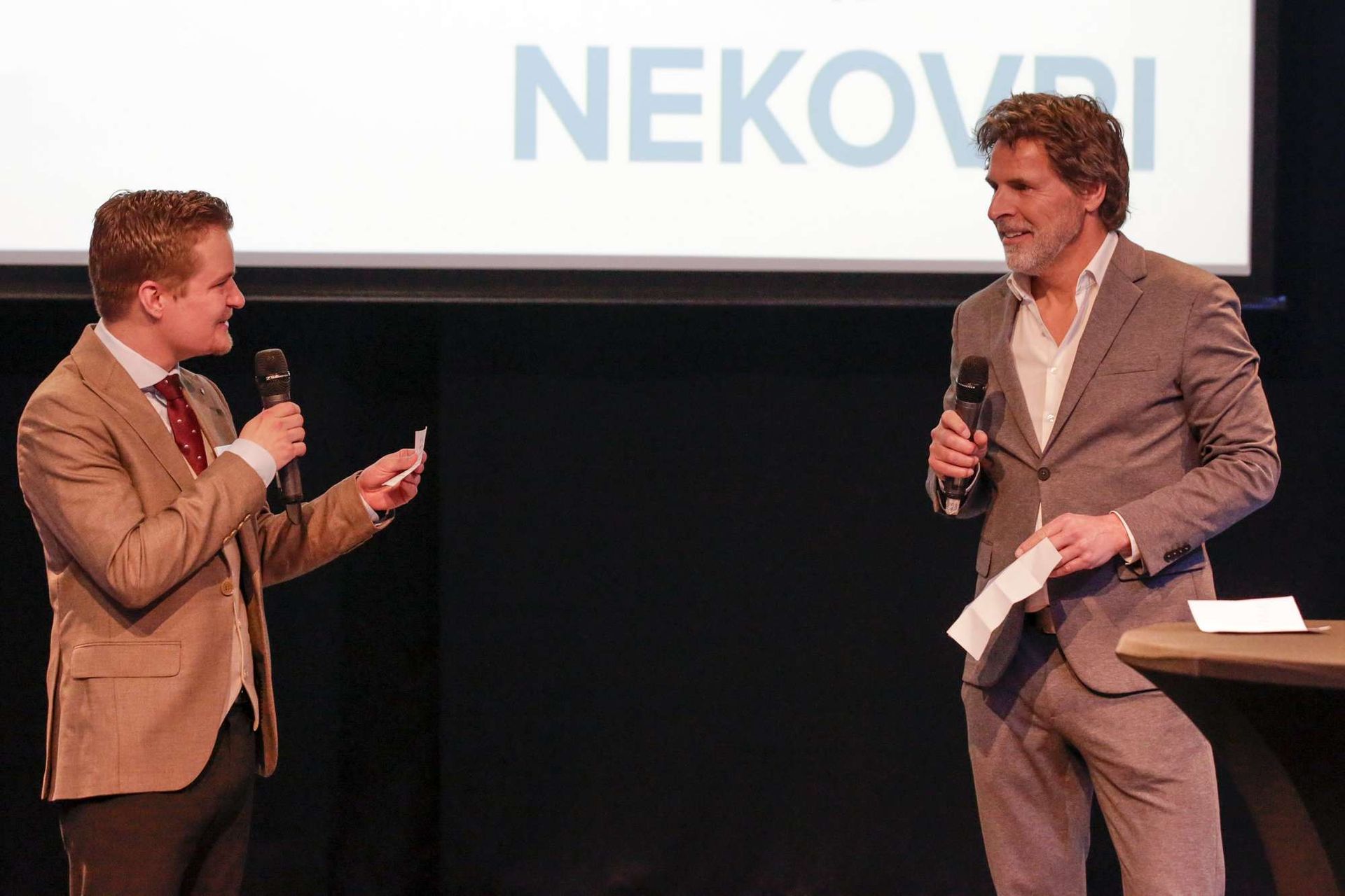 Twee mannen staan ​​voor een scherm waarop nekovri staat