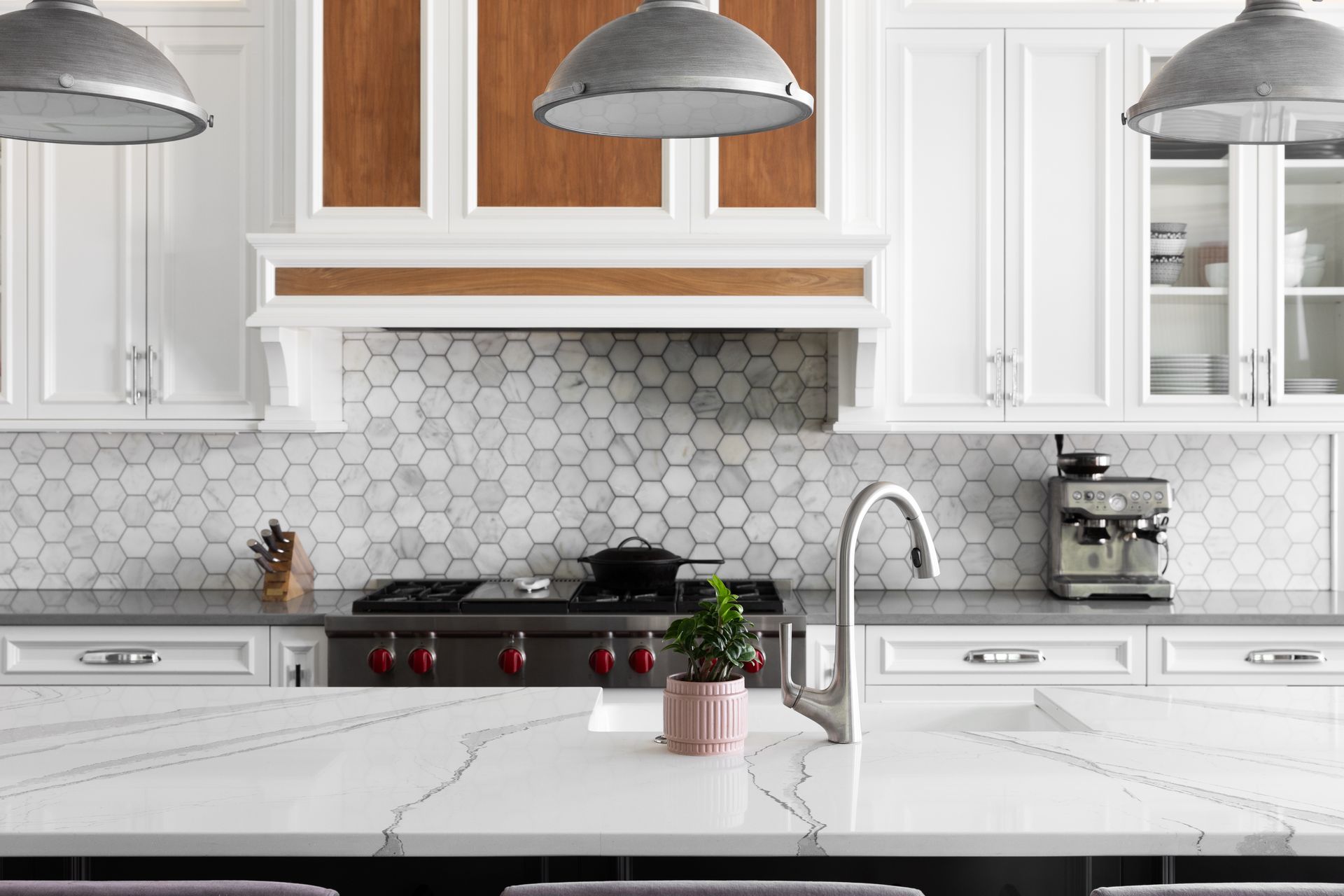Modern white kitchen with hexagon tile backsplash, stainless appliances, and marble island counter