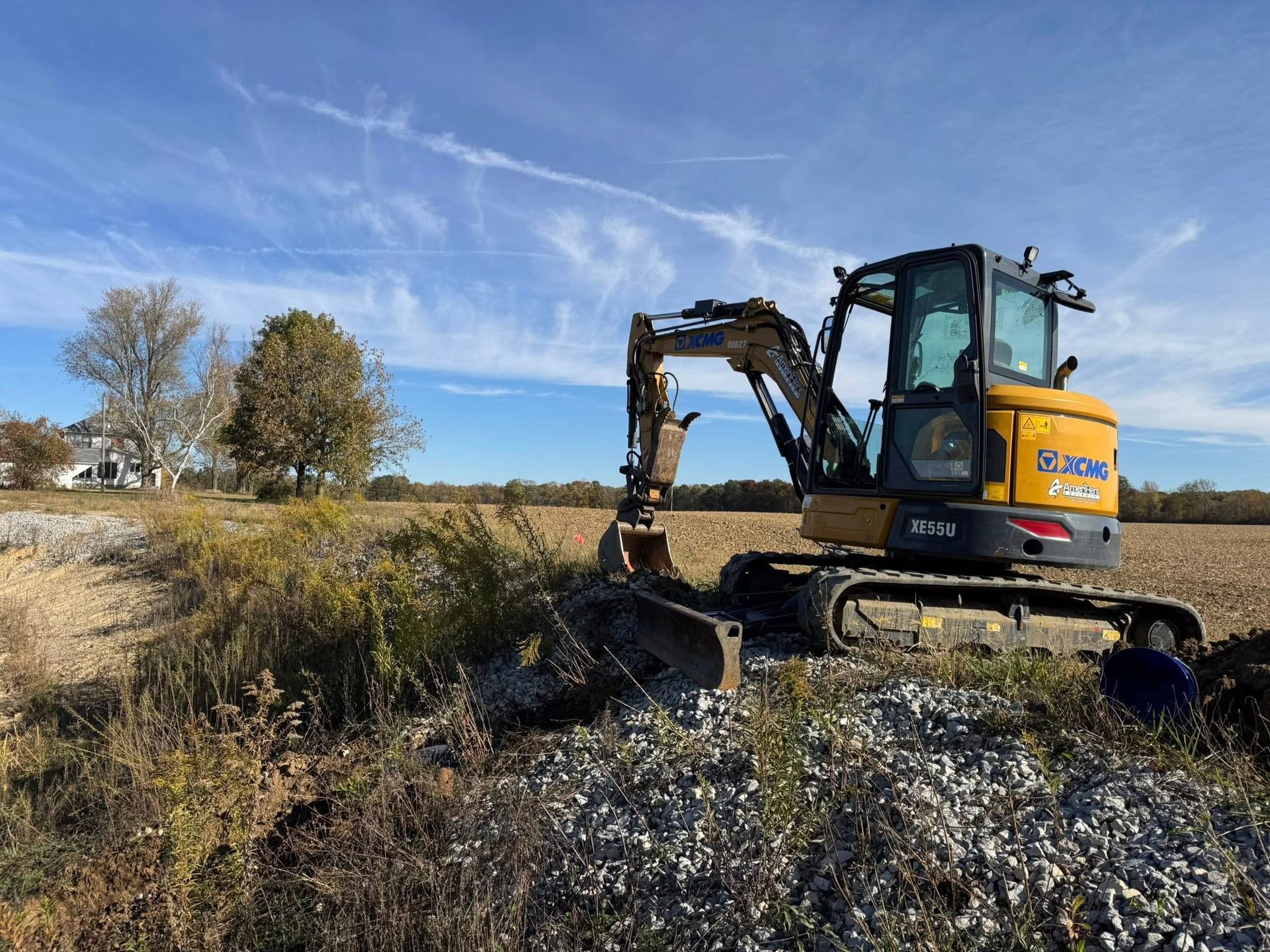 Yellow excavator working in a grassy field under a blue sky