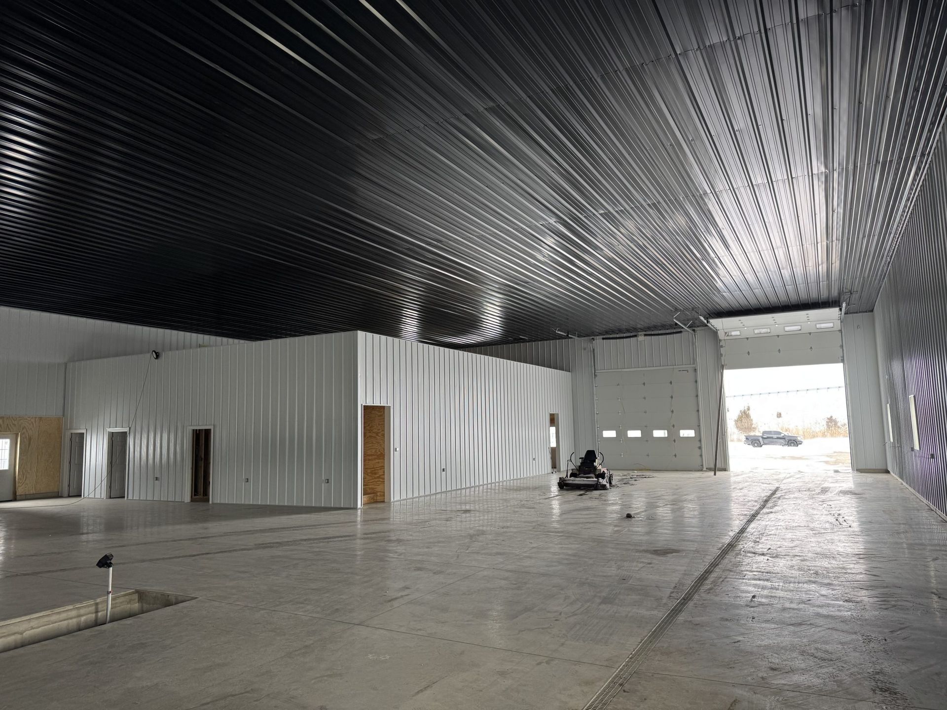 Empty industrial warehouse interior with high black ceiling, white walls, and a large open concrete floor
