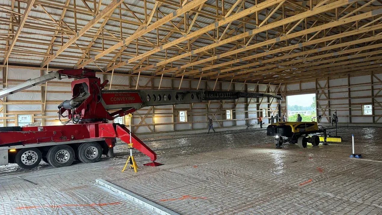 Construction site interior with red concrete pump truck and workers inside an unfinished building frame