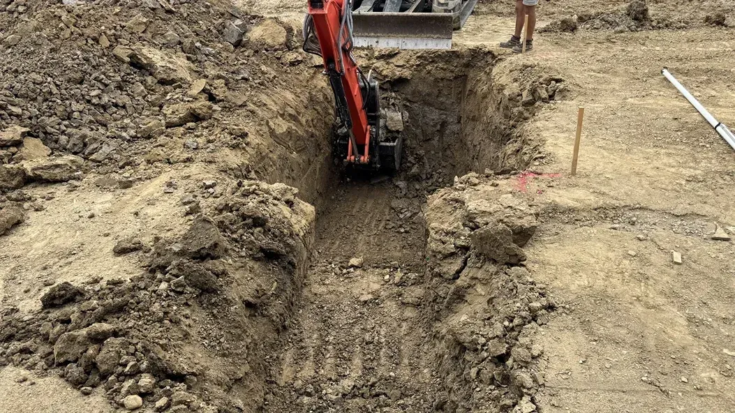 Excavator digging a trench in a muddy construction site