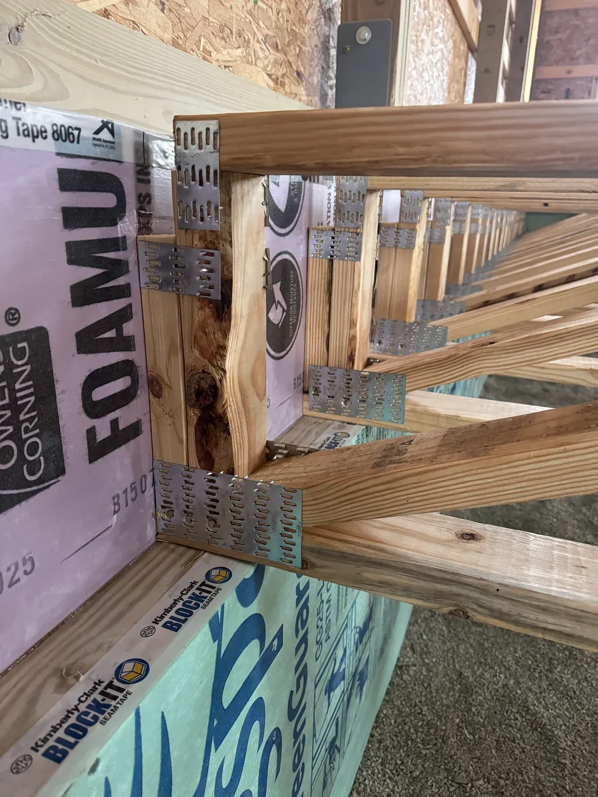 Wooden stair framing with pink and blue insulation boards in a construction space