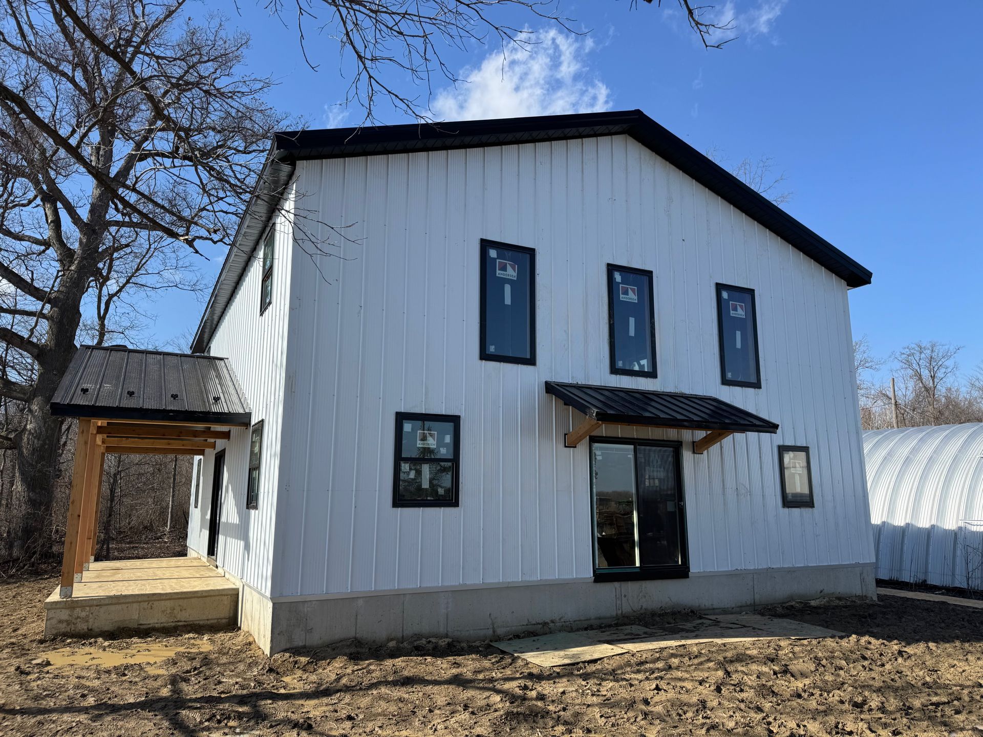 White two-story house with black trim and a small porch under a clear blue sky