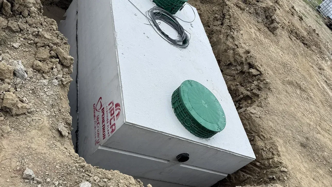White utility box partly buried in sand with green caps and a black ring on top
