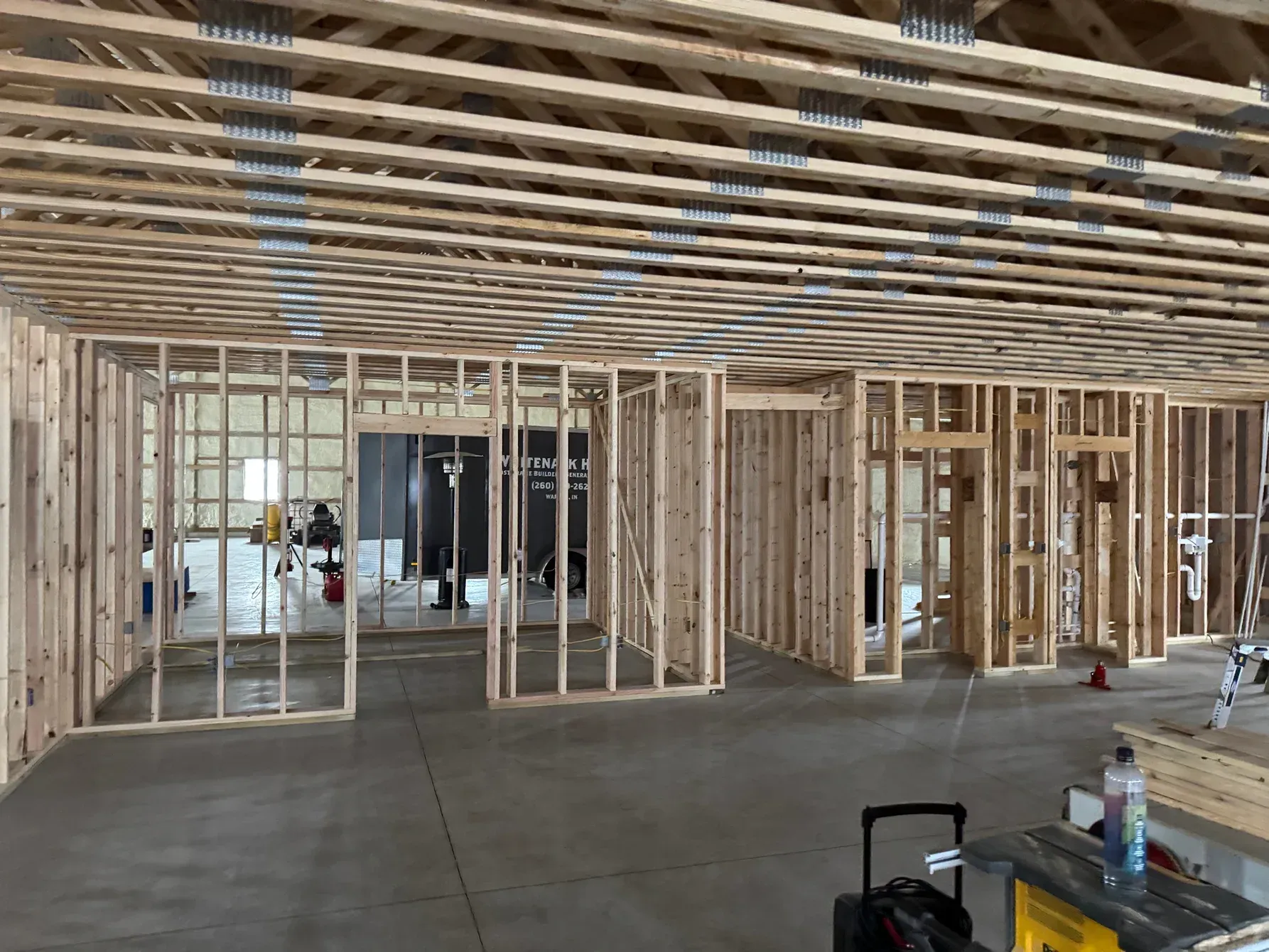 Interior of a framed house under construction with exposed wood studs and ceiling joists
