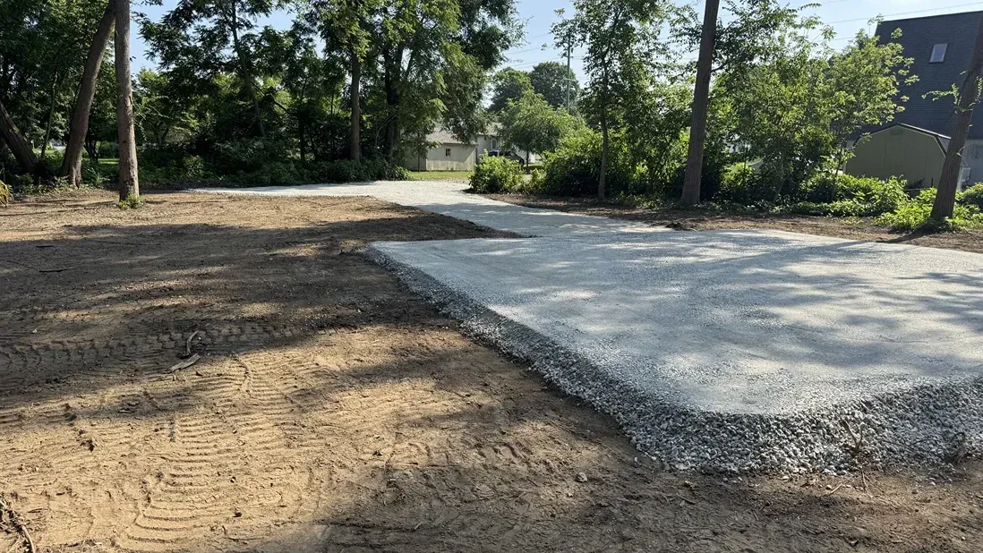 Fresh concrete slab beside a dirt path in a wooded outdoor area
