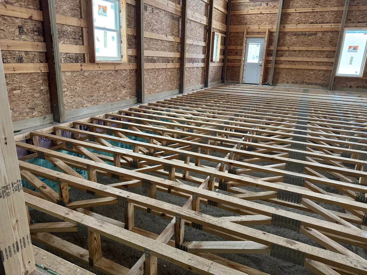 Bare interior of a house under construction with exposed wooden floor joists and framed walls
