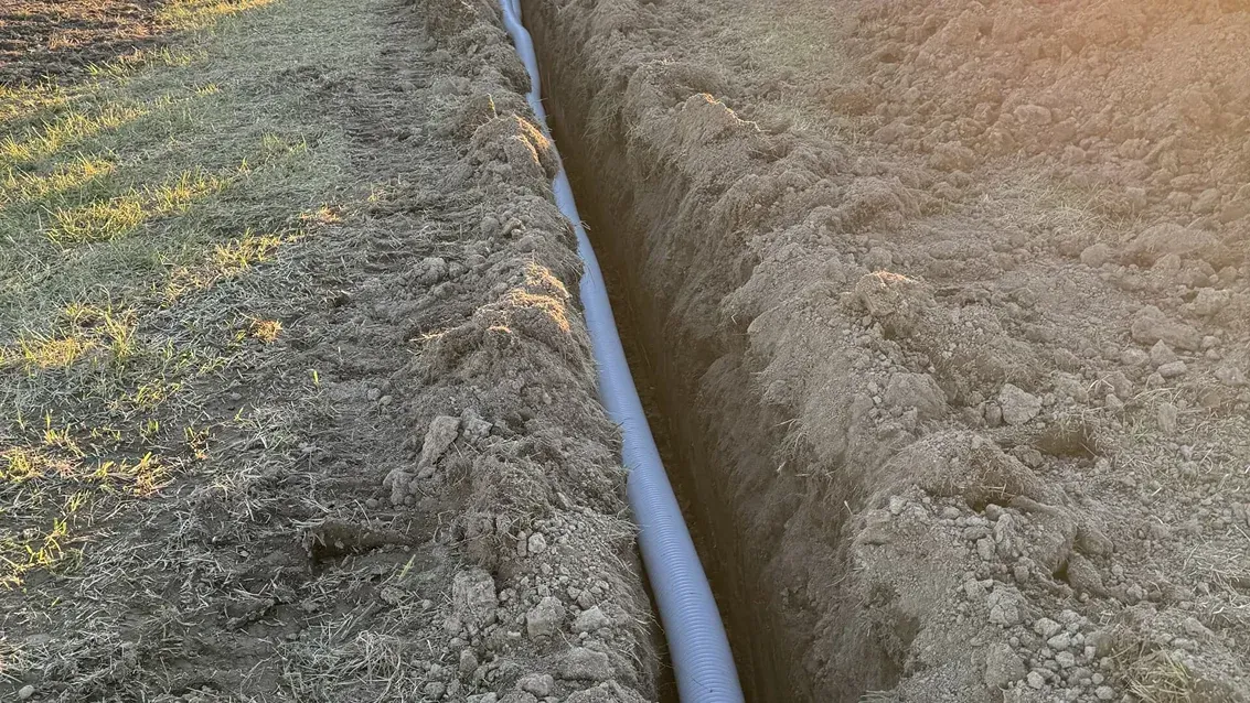 Close-up of a white pipe running through a narrow crack between rough stone surfaces.