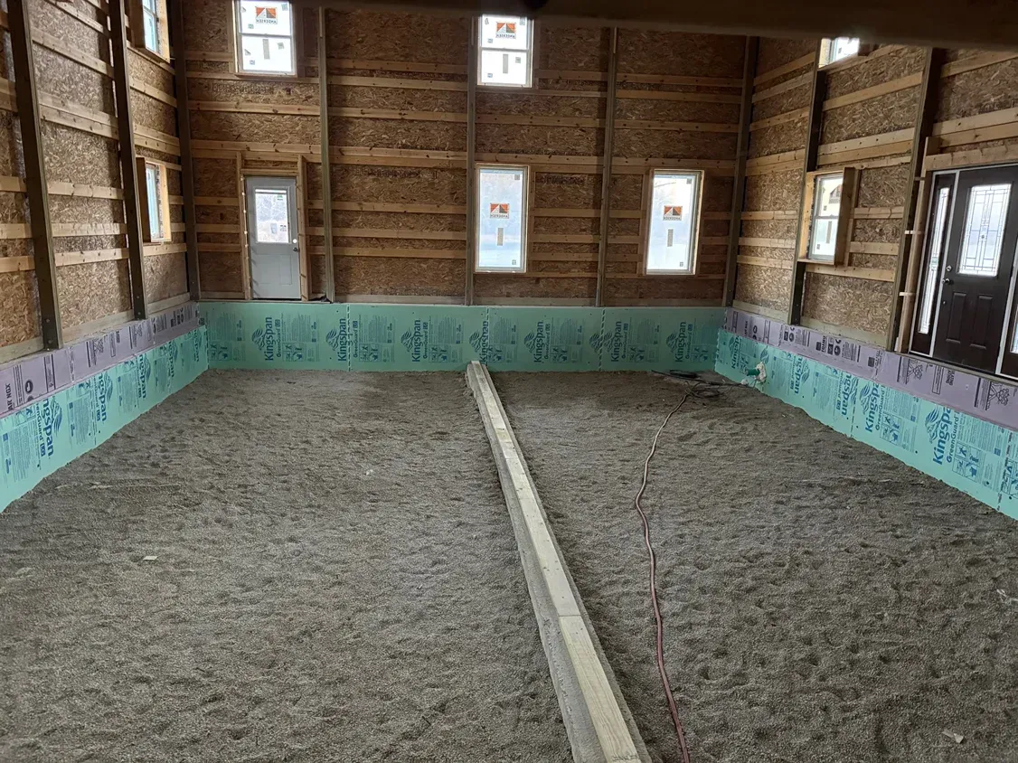 Empty unfinished room with dirt floor, exposed wood walls, and turquoise insulation around the perimeter