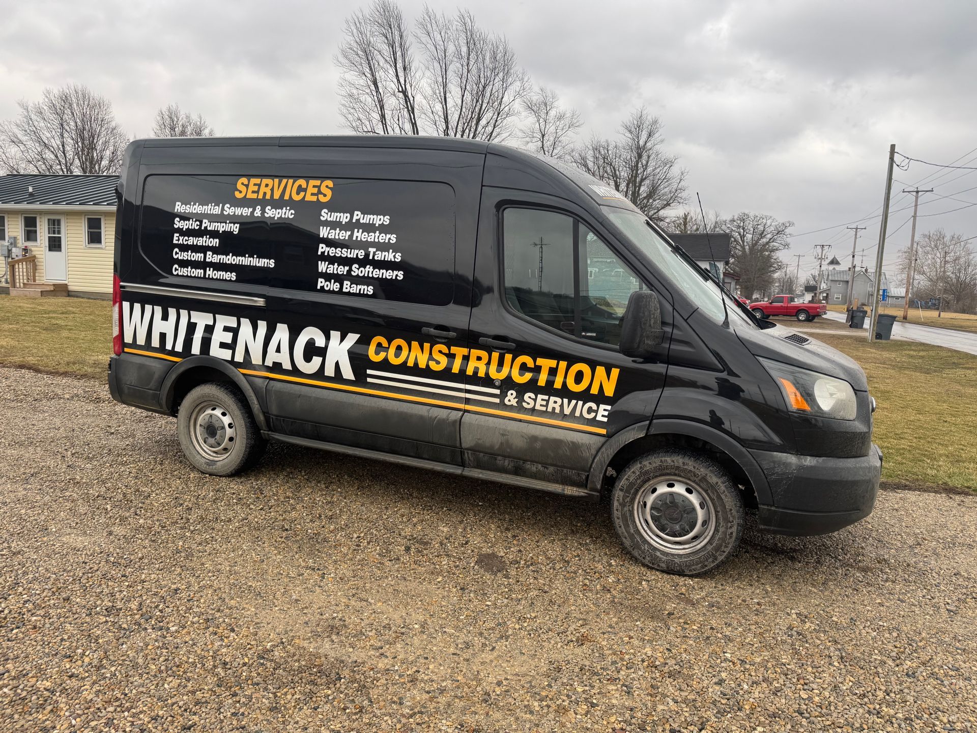 Black Whitenack Construction service van parked on gravel under a gray sky