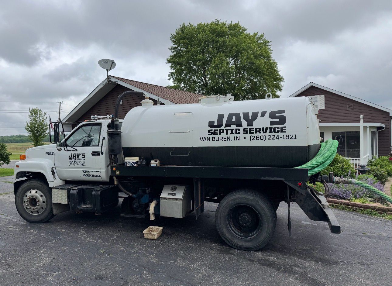 Jay's septic service truck parked in front of a house on a rainy day