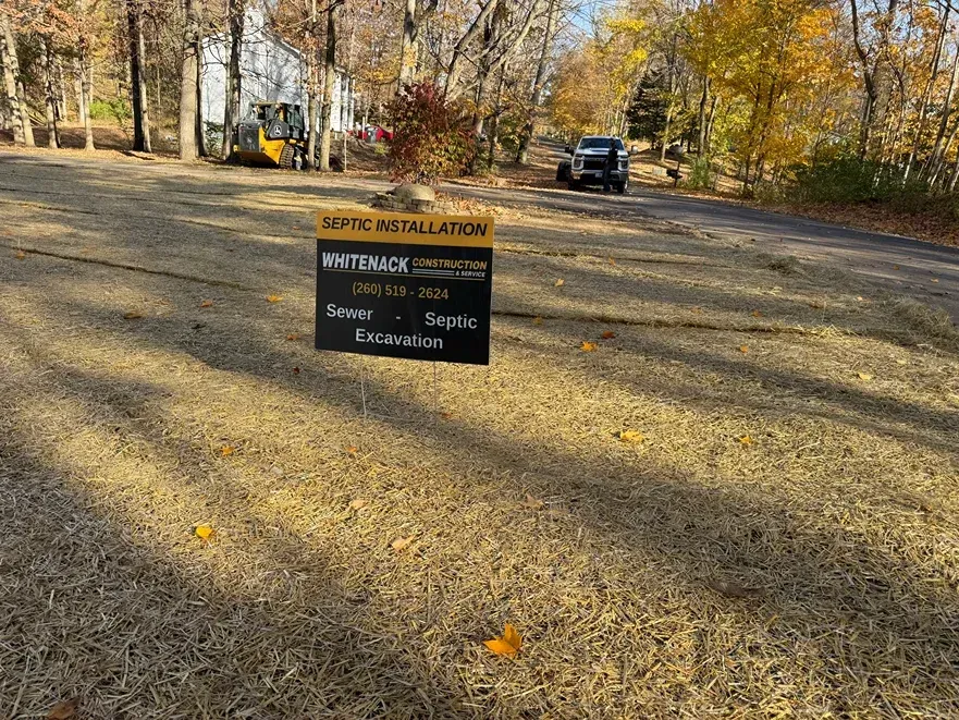 Autumn wooded path with a sign and a parked vehicle in the distance