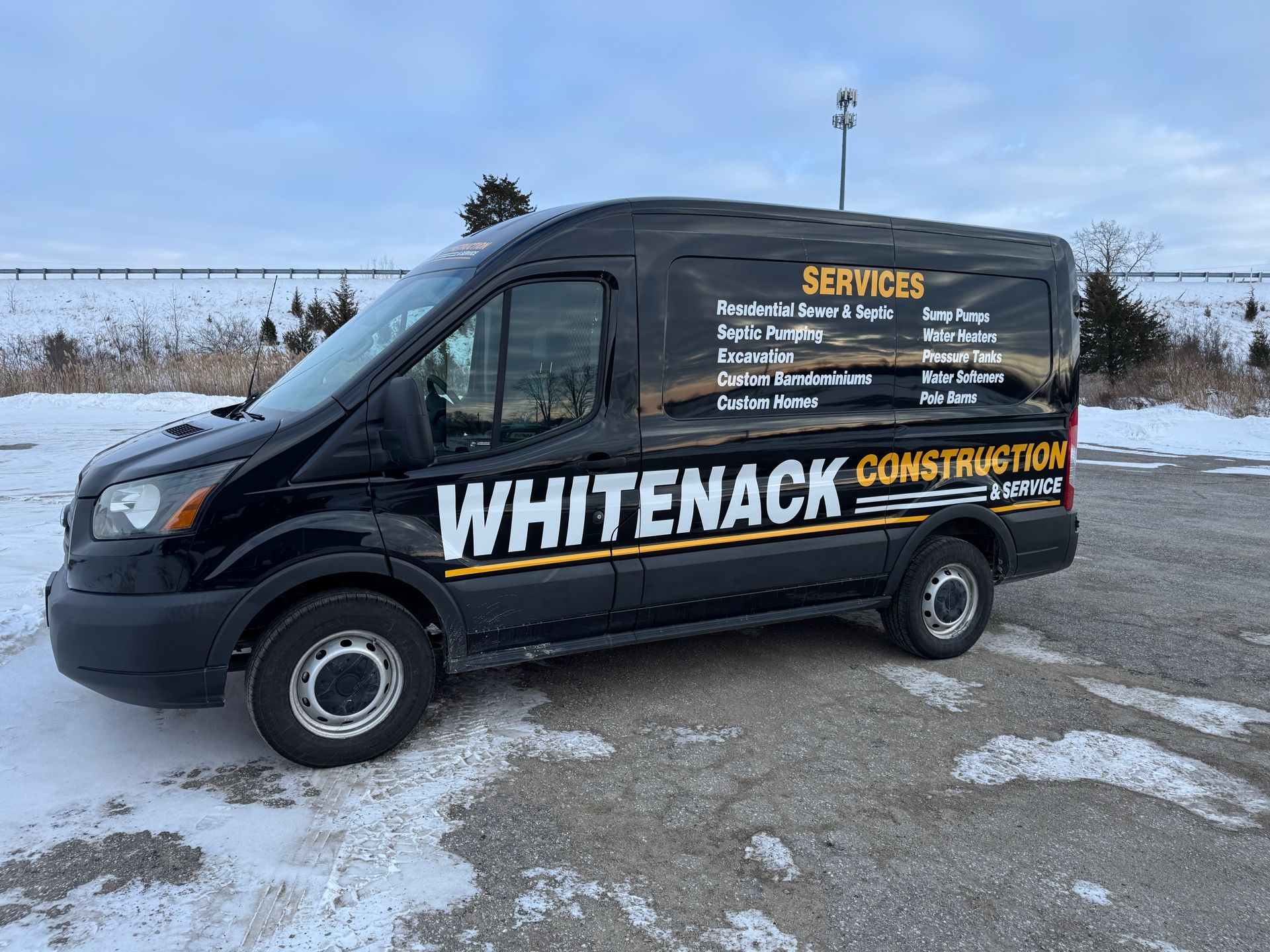 Black Whiteneck service van parked on snowy pavement with company lettering and logo on the side