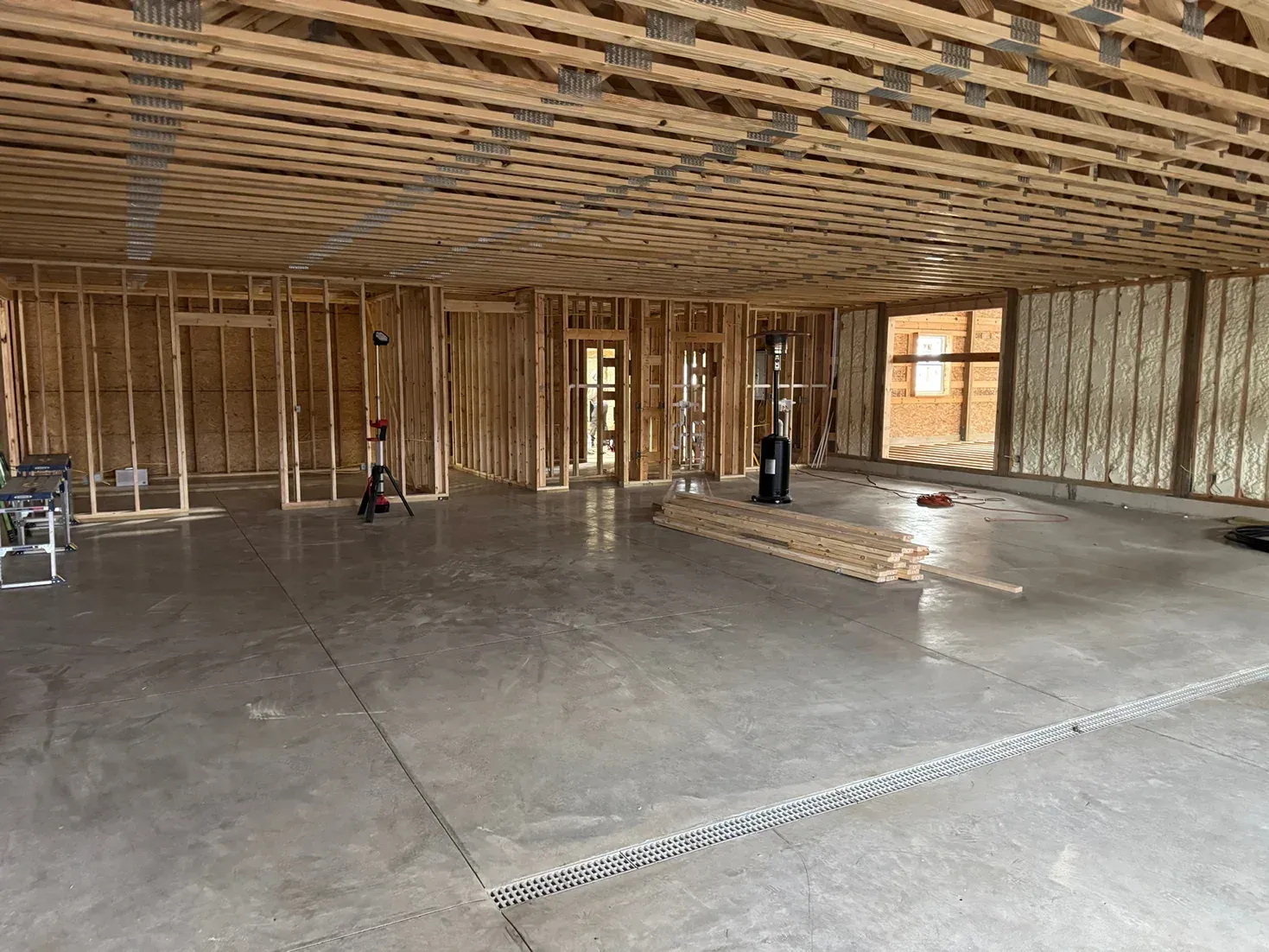Interior of a building under construction with exposed wooden framing and a concrete floor