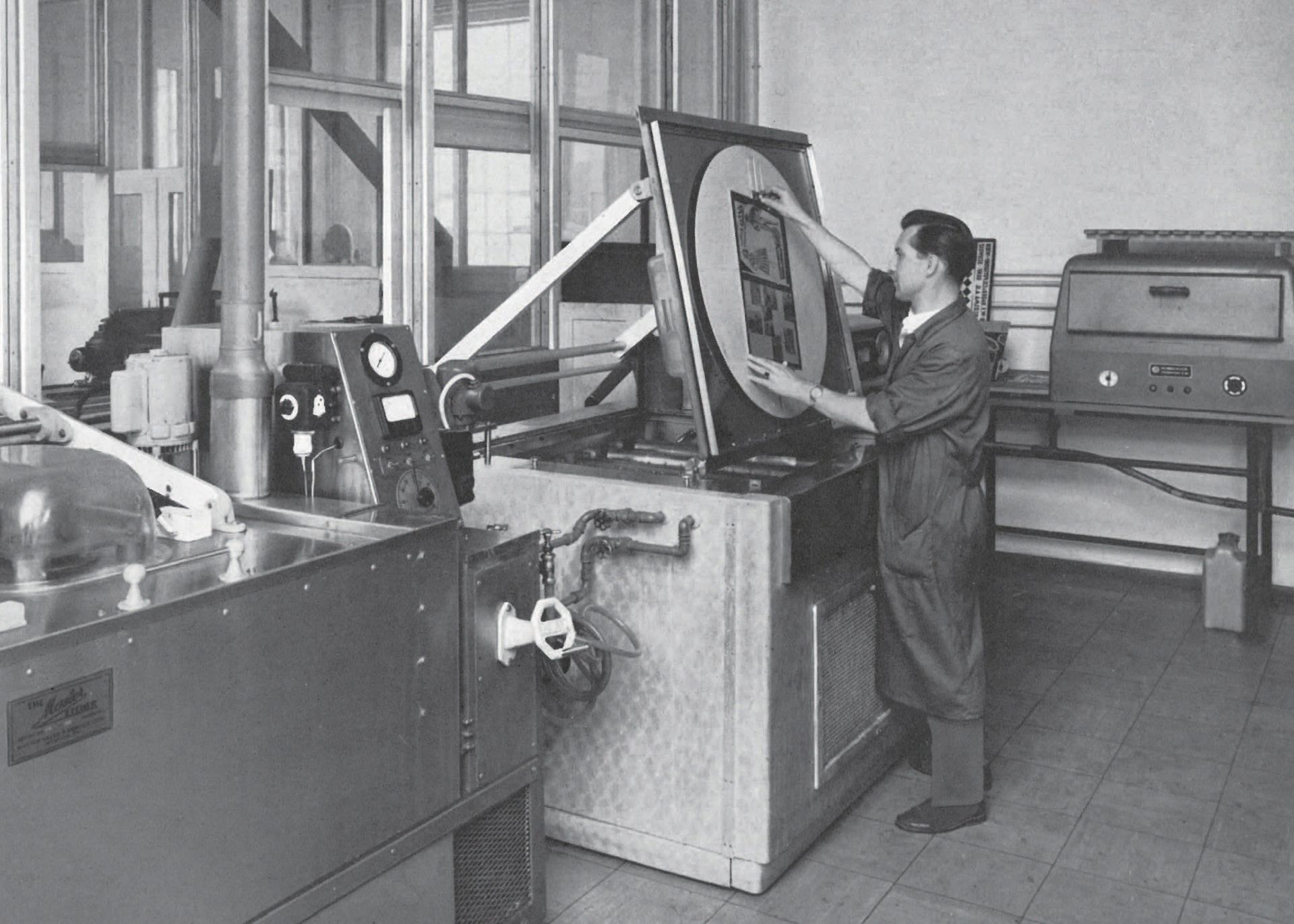 Ein Fabrikarbeiter bedient eine große Industriemaschine mit runder Frontplatte.