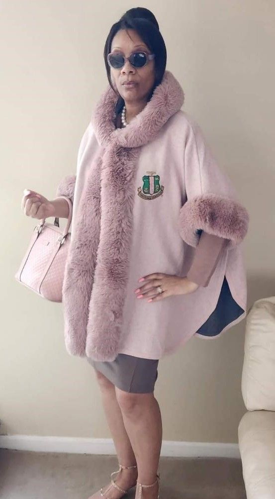 A woman is wearing a pink poncho with a fur collar and sleeves.