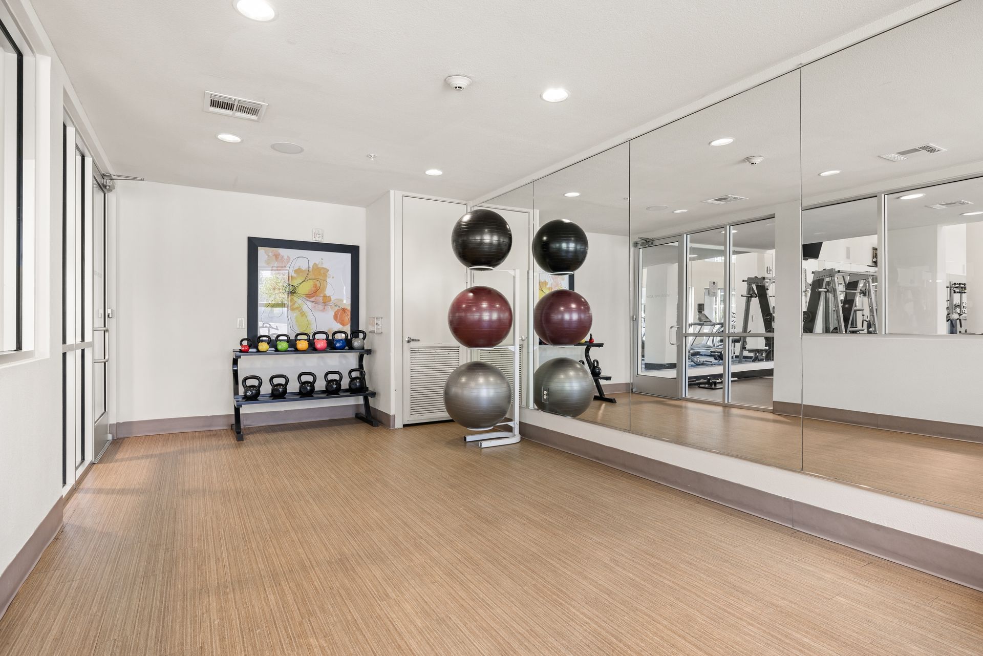 Bright fitness studio with mirrors, exercise balls, and a cork floor
