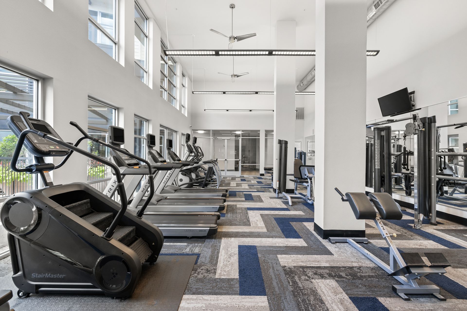Modern gym interior with treadmills, exercise machines, and patterned flooring